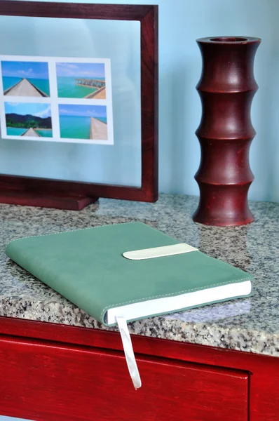 Note book with photo frame, vase on wooden desk — Stock Photo, Image