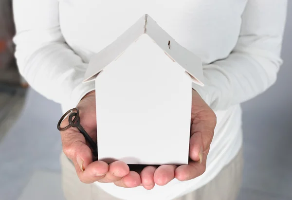 Vecchia donna mani tenendo casa modello e chiave — Foto Stock