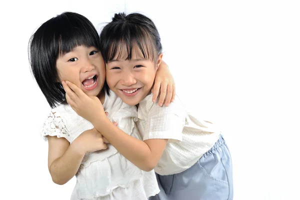 Twee gelukkige Aziatische kleine zusters knuffelen geïsoleerde — Stockfoto