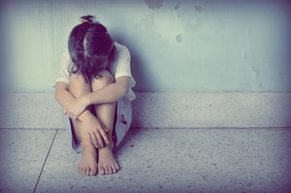 Sedih dan depresi gadis kecil duduk di dekat dinding — Stok Foto