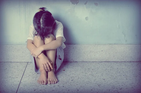 Duvara yakın oturan üzgün ve depresyonda küçük kız