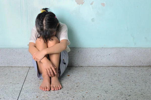 Duvara yakın oturan üzgün ve depresyonda küçük kız