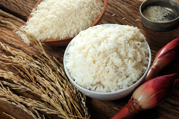 Arroz cocido, arroz sin cocer y arroz con cáscara sobre tabla de madera — Foto de Stock