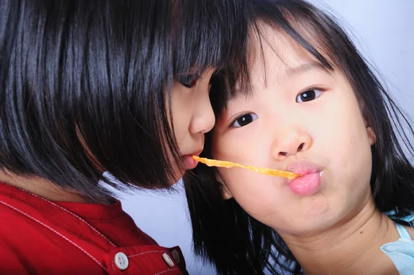 Двоє азіатських дітей їдять рибну закуску разом — стокове фото