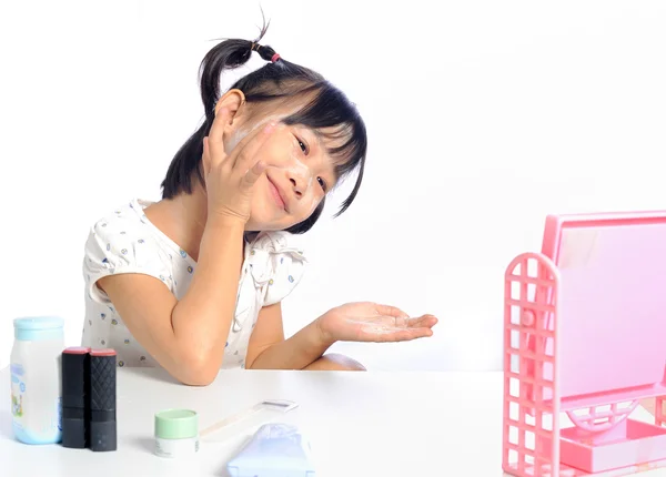 Усміхнена азіатська маленька дівчинка застосовує макіяж дитячий порошок її фа — стокове фото