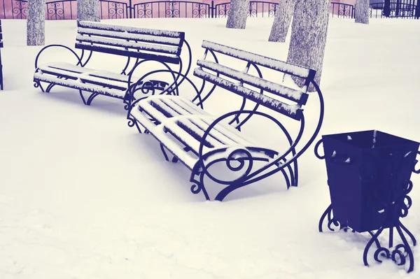 Outdoor furniture. Wood park bench with urn. Winter park with snow surface bench. Park bench isolated. Two benches in the winter park.