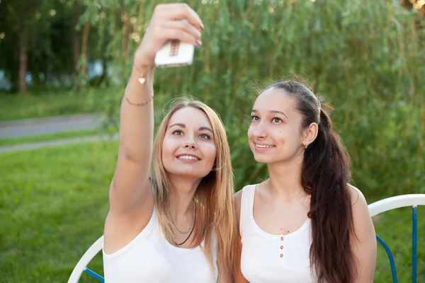 Smiling teenage girls taking self photo with cellular phone — Stock Photo, Image