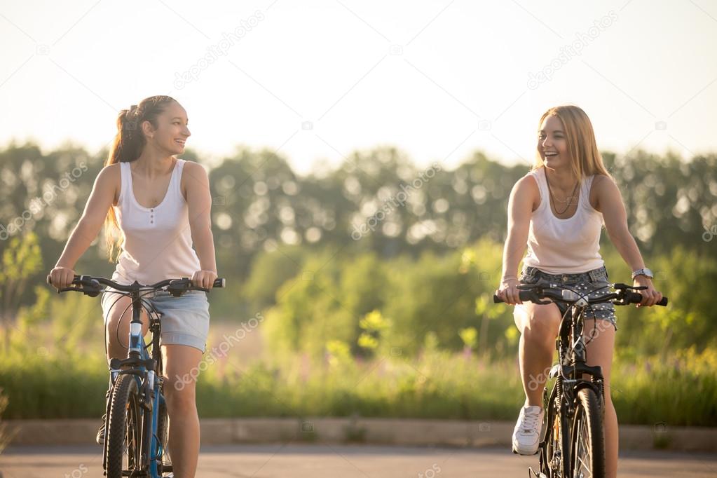Two laughing young women driving bicycles