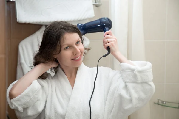 Young woman blowing her hair with hairdryer — Zdjęcie stockowe