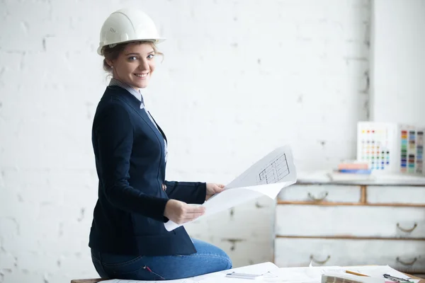 Smiling woman in white helmet with blueprint — Stock Photo, Image