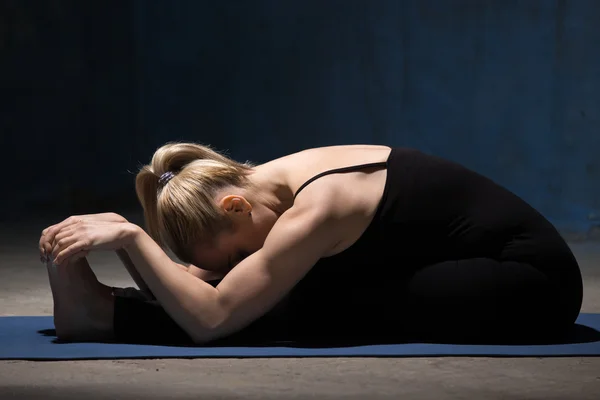 Schöne Yoga-Frau in Paschimothanasana-Pose — Stockfoto