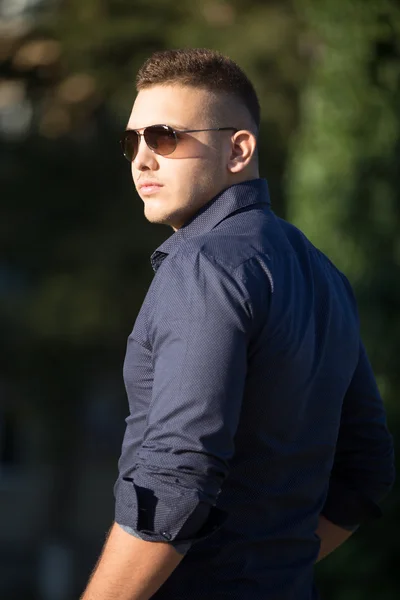 Young man in sunglasses walking in park — Stock Photo, Image