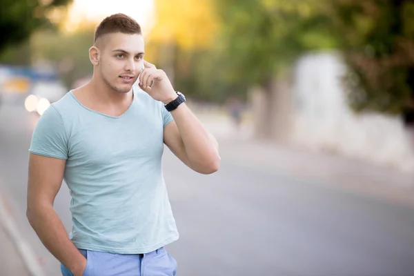 Jongeman op smartphone op stad straat — Stockfoto