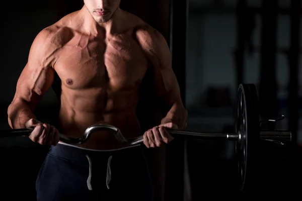 Muscular man lifting a barbell in gym — Stock Photo, Image