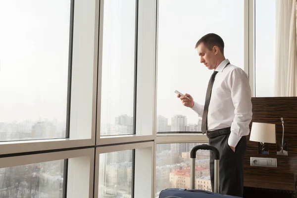 Young businessman using smartphone in hotel room — Stock Photo, Image