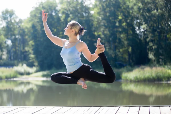 Yogi female doing One-legged king pigeon pose in mid air — Stock fotografie