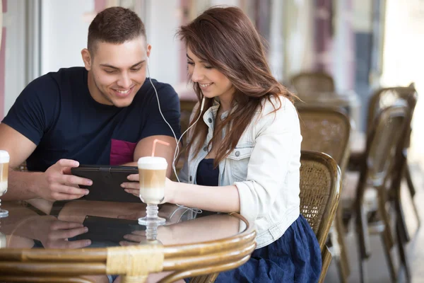 Casal sentado com fones de ouvido em um café — Fotografia de Stock