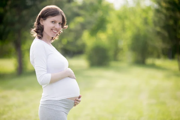 Happy pregnant woman on late pregnancy stage posing in park — Stock Photo, Image