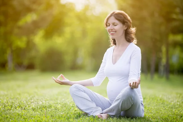 Healthy pregnant woman relaxing on grass in park — Stock Photo, Image