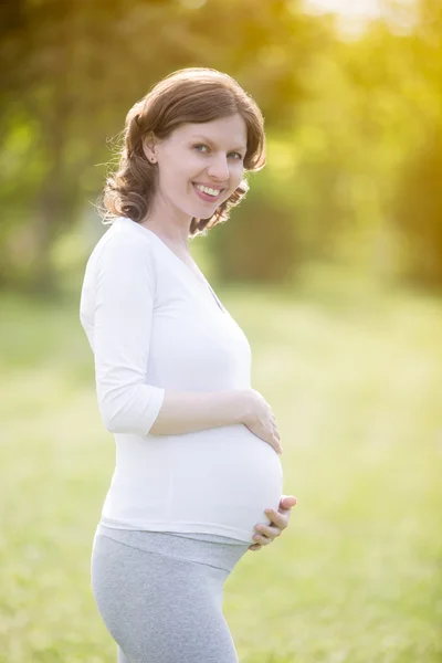Šťastná těhotná žena z pozdního těhotenského období chůze v parku — Stock fotografie