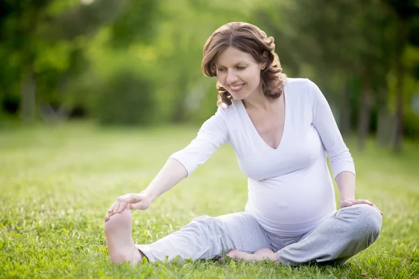 Šťastná těhotná žena cvičková v parku — Stock fotografie