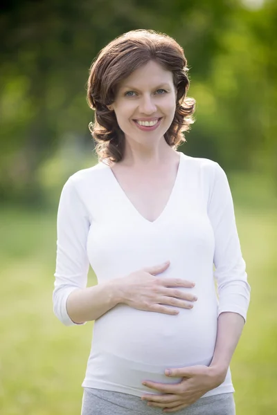 Portrait of happy pregnant female touching her belly — Stock Photo, Image