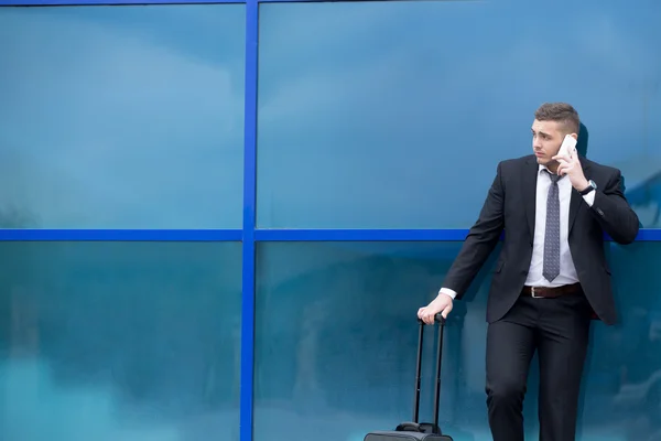 Portrait of young traveler in suit standing with suitcase and ma — Stock Photo, Image