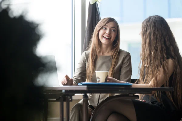 Two young beautiful women chatting in cafe