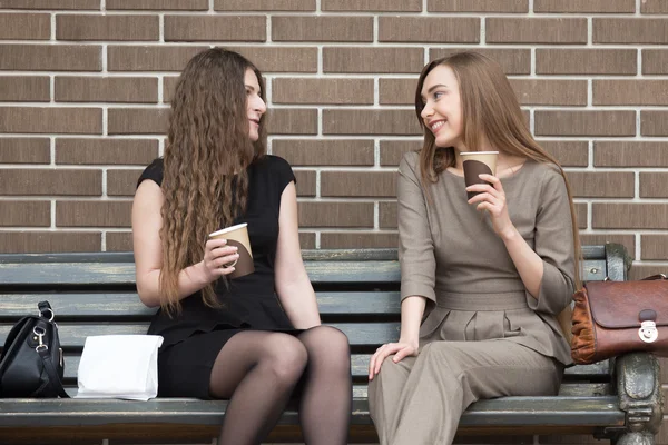 Dos mujeres hermosas jóvenes sosteniendo tomar café y charlar — Foto de Stock