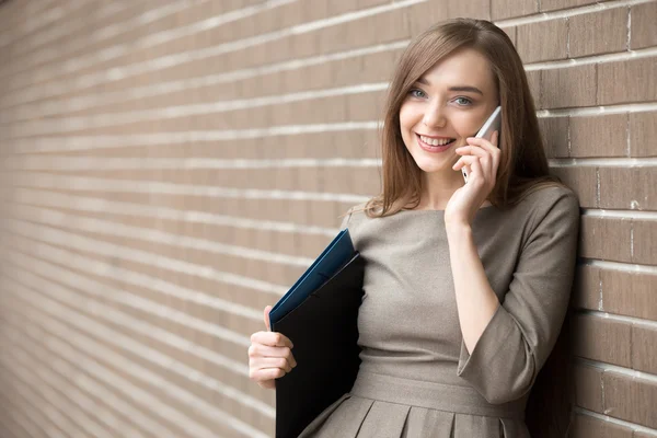 Porträtt av ung kvinna pratar på telefon och tittar på kamera o — Stockfoto
