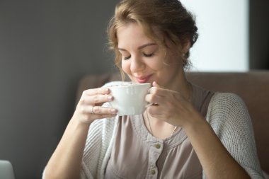 Kapalı gözlü aromatik kahve içen gülümseyen mutlu kadın