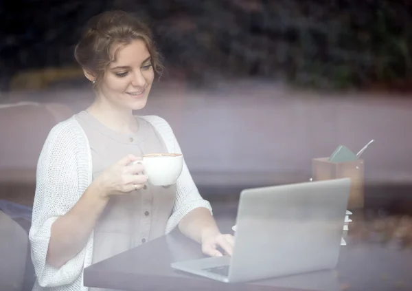 在咖啡店里使用笔记本电脑的现代女性。吹风射击 — 图库照片