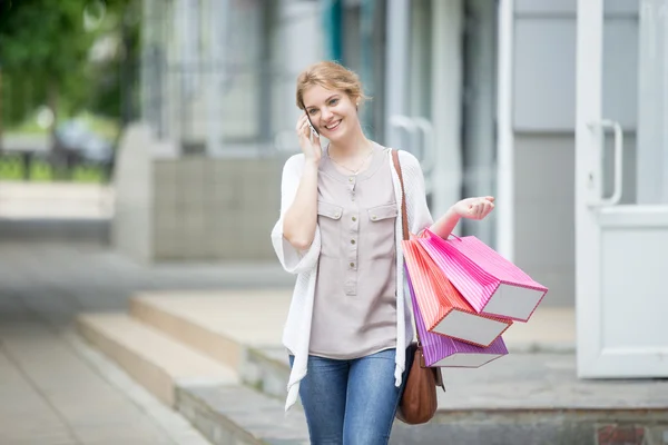 Retrato de una joven sonriente en el teléfono móvil durante las compras — Foto de Stock