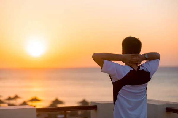 Ung man njuter av havsutsikten från balkongen — Stockfoto