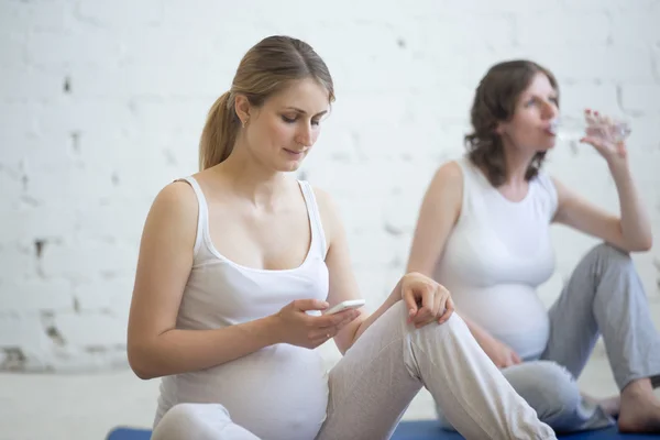 Těhotná žena pomocí smartphone app před fitness třída — Stock fotografie