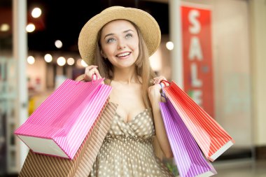 Woman in shopping centre smiling holding shopping bags