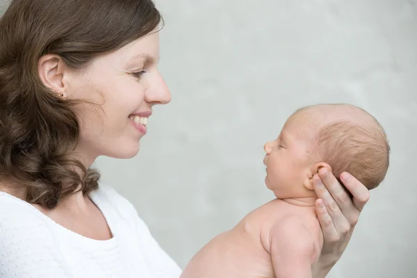 Portrait of young mother and her newborn baby. Side view — Stock Photo, Image