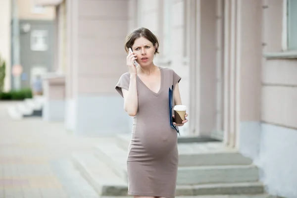 Расстроенная беременная деловая женщина по телефону — стоковое фото