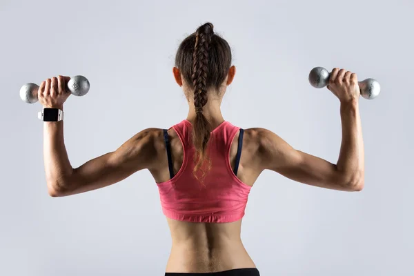 Mujer deportiva haciendo ejercicio con pesas. Vista trasera —  Fotos de Stock