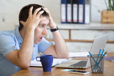 Young shocked office man looking at laptop computer
