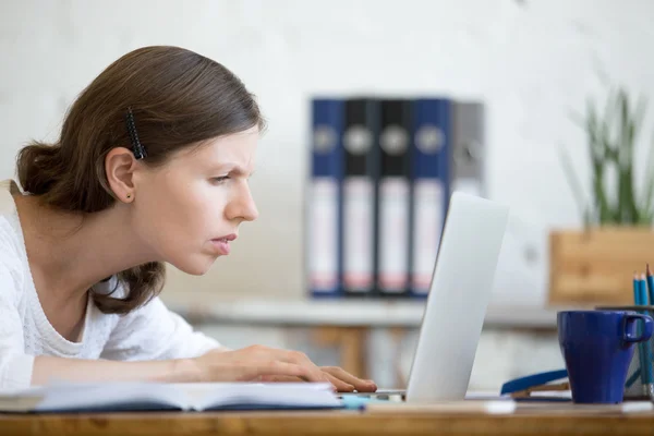 Young concerned office woman looking at laptop computer — Stok fotoğraf