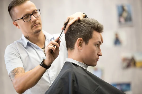 Profile view portrait of attractive young man getting haircut