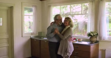 Ev mutfağında dans eden mutlu yaşlı çift.