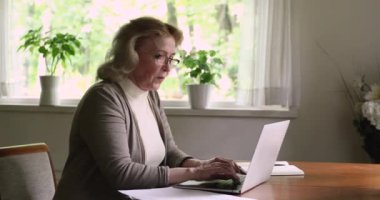 Dizüstü bilgisayar kullanan bir kadın e-banka uygulaması aracılığıyla faturaları ödüyor.