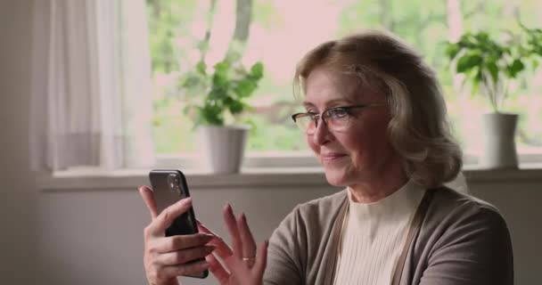 Äldre kvinna använder smartphone bläddra nyhetsflöde, spendera tid på nätet — Stockvideo