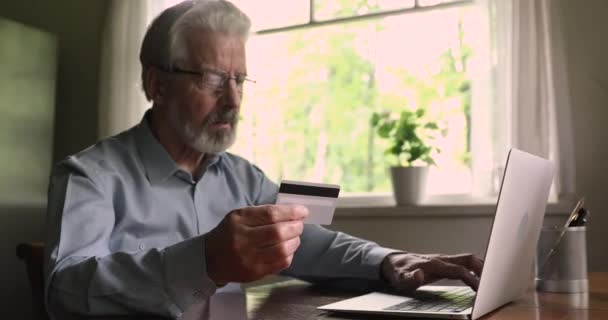 Зріла людина використовує ноутбук вводить дані картки робить покупку в Інтернеті — стокове відео