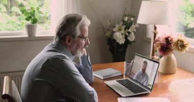 Genç ve olgun iş adamları video görüşmesiyle uzaktan konuşuyor.