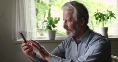 Neşeli yaşlı adam akıllı telefonu tut. Eğleniyor. Modern teknolojiyi kullan.