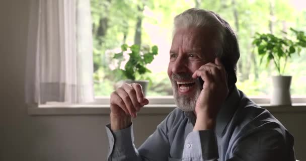 Oudere man met smartphone genieten van een aangenaam gesprek — Stockvideo