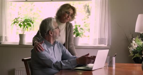 Ηλικιωμένοι σύζυγοι χρησιμοποιούν φορητό υπολογιστή διαβάσει μεγάλη είδηση γιορτάσουν τη νίκη λαχείο — Αρχείο Βίντεο